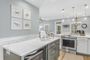A modern kitchen with a central island, stainless steel appliances, and a pendant light fixture.