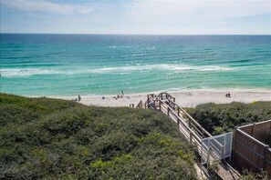 Une plage avec une promenade en bois menant au rivage, entourée de verdure.