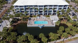 A multi-story hotel with a central pool, surrounded by palm trees and a parking area. - 500 Ft from Beach! 3 Pools (1 Seasonally Heated)! Ground Floor Condo! ~ Cabana 103 at Gulf Place on 30A (Santa Rosa Beach)