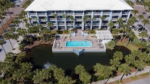 A multi-story hotel with a central pool, surrounded by palm trees and a parking area. - 500 Ft from Beach! 3 Pools (1 Seasonally Heated)! Ground Floor Condo! ~ Cabana 103 at Gulf Place on 30A (Santa Rosa Beach)
