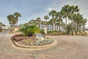Een hotel ingang met een verharde oprit, palmbomen en een bord met de naam 'GULFPLACE'.
