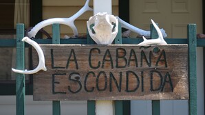 Une enseigne en bois portant l’inscription « LA CABANA ESCONDIDA » et ornée de bois de cerf décoratifs.