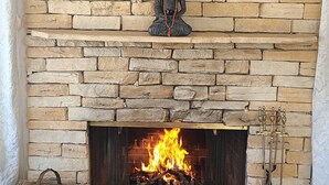 A stone fireplace with a Buddha statue above it, a fire burning, and a decorative item on the mantel. - Mid Century Modern - Direct Park Access with Stargazing Patio (Joshua Tree)