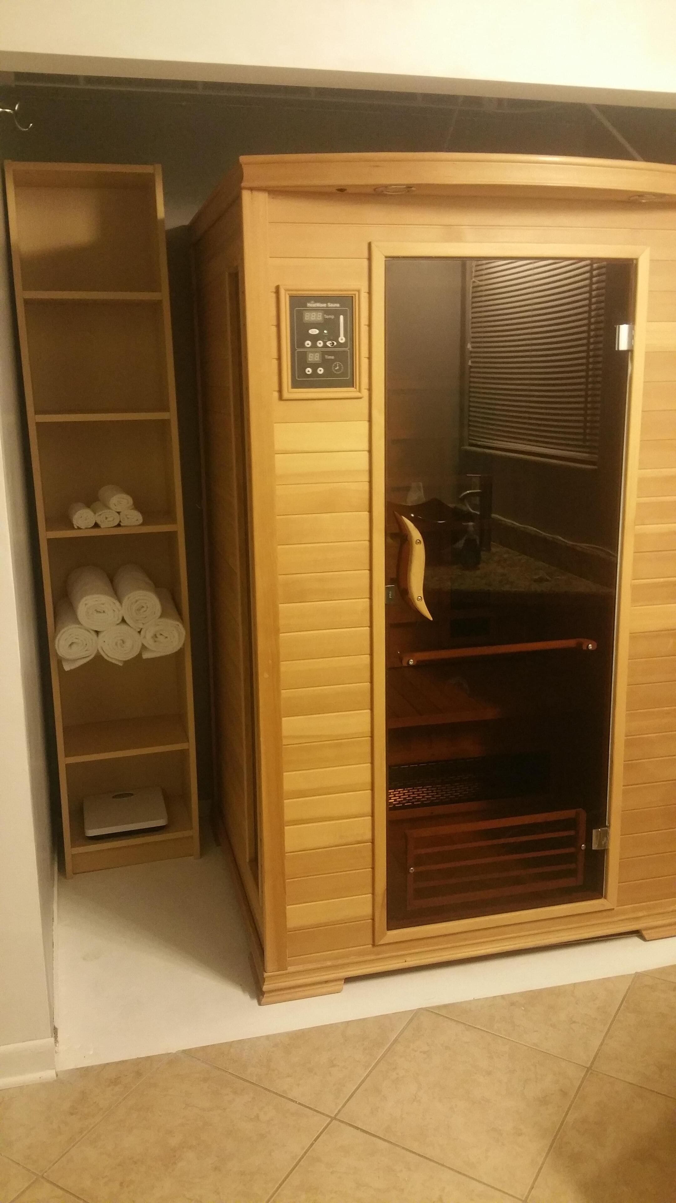Eine Sauna mit Bedienfeld, einer Holzbank und Regalen mit Handtüchern.