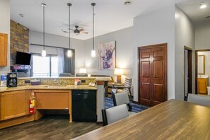 Una habitación de hotel con cocina, una mesa de comedor y una puerta grande de madera.