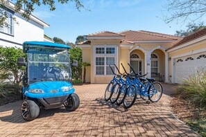 A blue golf cart parked in front of a house with a garage and a bicycle rack with three bicycles. - Golf Cart & 4 Bikes! Walk to the Beach & the Pool! One Story Home in Gated Comm! ~ Our Little Peace of Paradise at Destiny West (Destin)