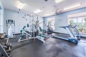 Ein Fitnessraum mit Trainingsgeräten, Laufband und großen Fenstern.