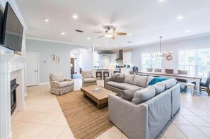 A spacious living room with a fireplace, a large sofa, and a coffee table. - Golf Cart & 4 Bikes! Walk to the Beach & the Pool! One Story Home in Gated Comm! ~ Our Little Peace of Paradise at Destiny West (Destin)