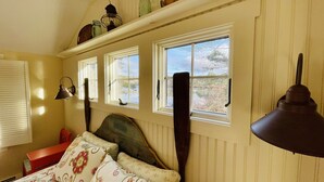 Une chambre avec un lit, une fenêtre donnant sur un lac et une lampe.