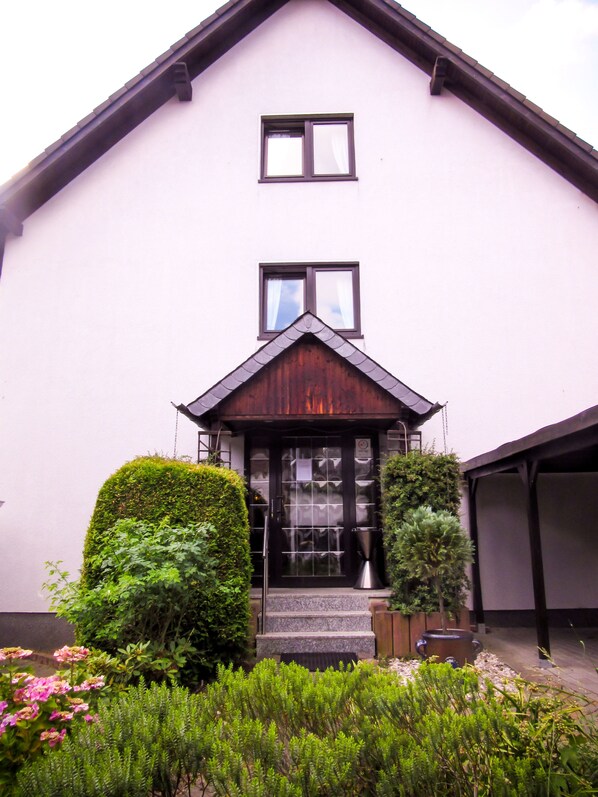 A house with a dark wooden front door, a small porch, and a garage. - Hotel Zur Flora (Essen)