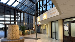 A spacious lobby with a large glass ceiling, a central seating area with a patterned ottoman, and a reception desk. - Gulf-Front Phoenix X 3BR  Stunning Balcony Views,  (Orange Beach)