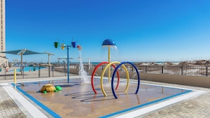 A water play area with colorful rings and a water fountain, surrounded by a pool and a beach view. - Gulf-Front Phoenix X 3BR  Stunning Balcony Views,  (Orange Beach)