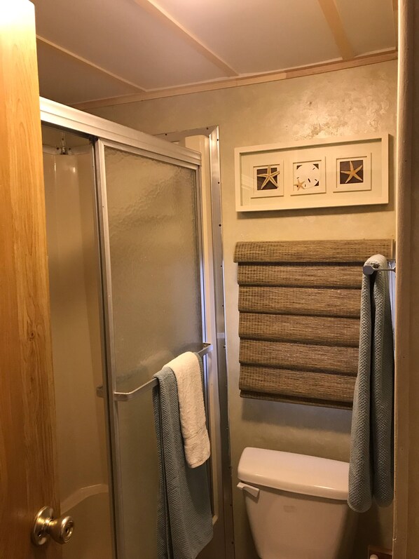 Een badkamer met douche, toilet en handdoekrek.