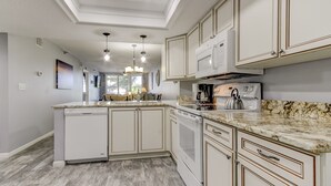 A kitchen with white cabinetry, granite countertops, and a dishwasher.