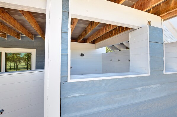 A room with a sloped ceiling, wooden beams, and a window with a view of palm trees.