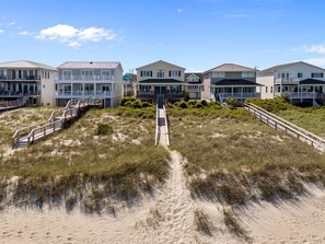 A beachfront property with multiple houses, a sandy path leading to the beach, and a wooden staircase. - Namaste at the Beach Oceanfront House, Dog Friendly, Private Beach Access! (Kure Beach)