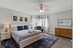 A bedroom with a bed, nightstands, a chair, a dresser, and a ceiling fan. - Namaste at the Beach Oceanfront House, Dog Friendly, Private Beach Access! (Kure Beach)