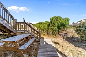A wooden deck leading to a picnic table area with a metal signpost. - Namaste at the Beach Oceanfront House, Dog Friendly, Private Beach Access! (Kure Beach)
