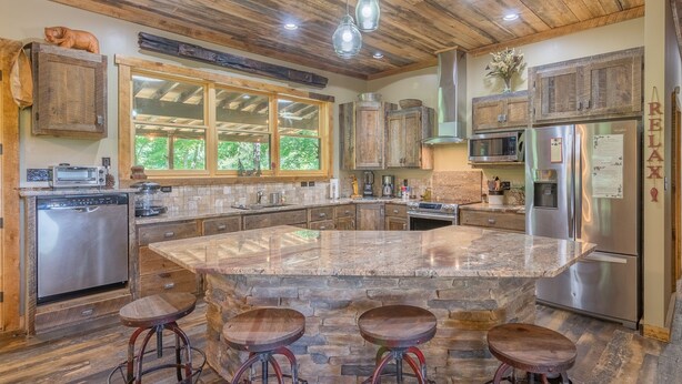 A spacious kitchen with a large island, wooden cabinets, and stainless steel appliances. - Watauga River Cabins- Cedar Cabin  (Johnson City)