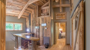 A rustic wooden interior with a staircase, a small table, and a bed in the background. - Watauga River Cabins- Cedar Cabin  (Johnson City)