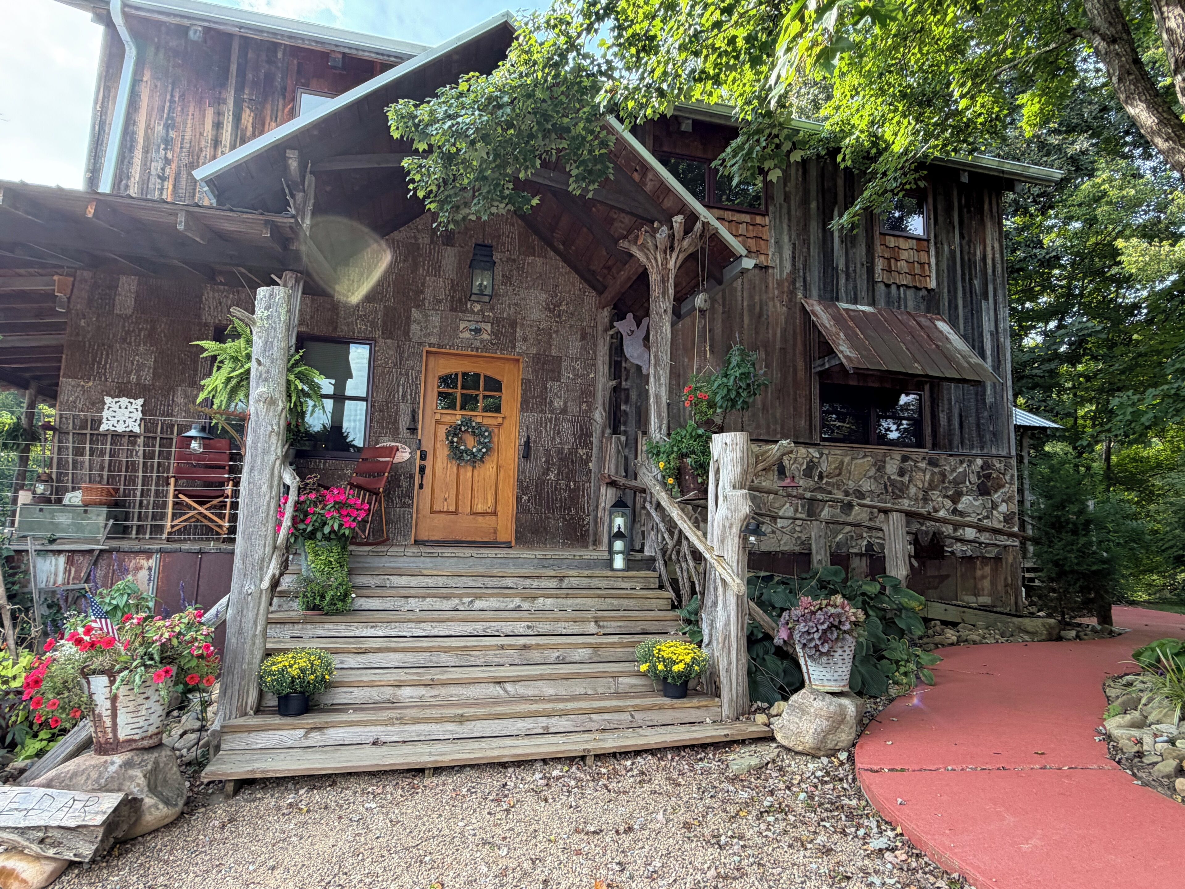 Un bâtiment rustique en bois, doté d’une porte en bois, de marches menant à l’entrée et d’un chemin rouge.