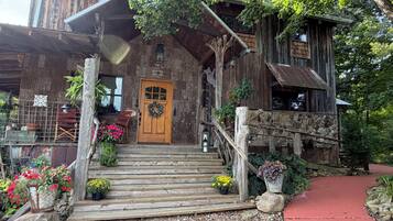 Un bâtiment rustique en bois, doté d’une porte en bois, de marches menant à l’entrée et d’un chemin rouge.