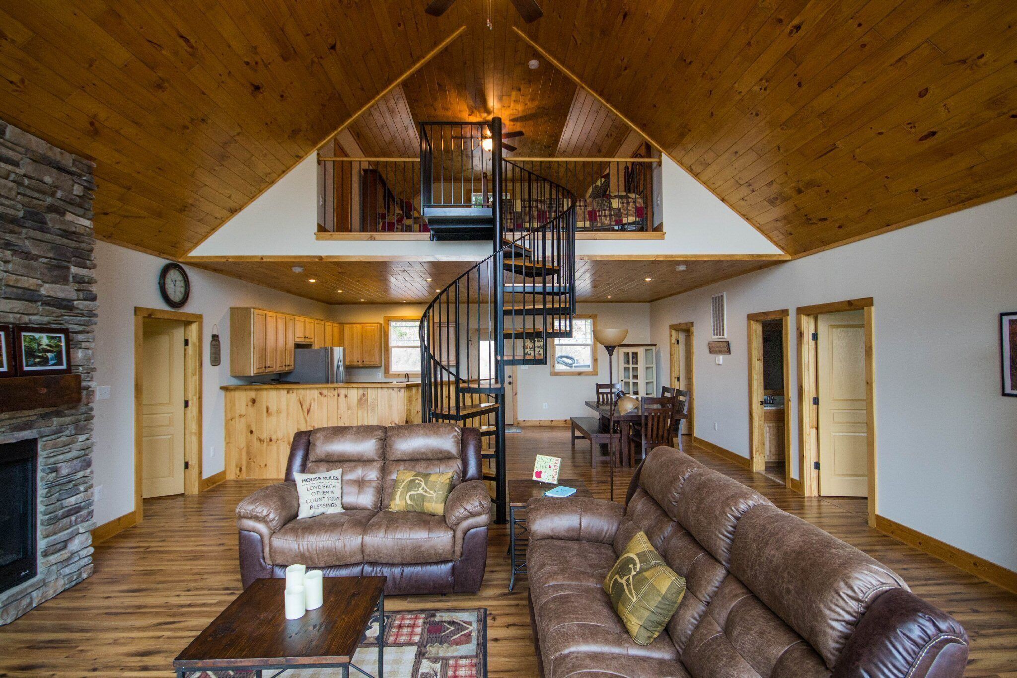 Amplio espacio tipo loft con techo alto, chimenea, sofás de cuero, zona de comedor y escalera de caracol.
