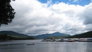 A lake with boats docked on the shore, surrounded by mountains and trees.