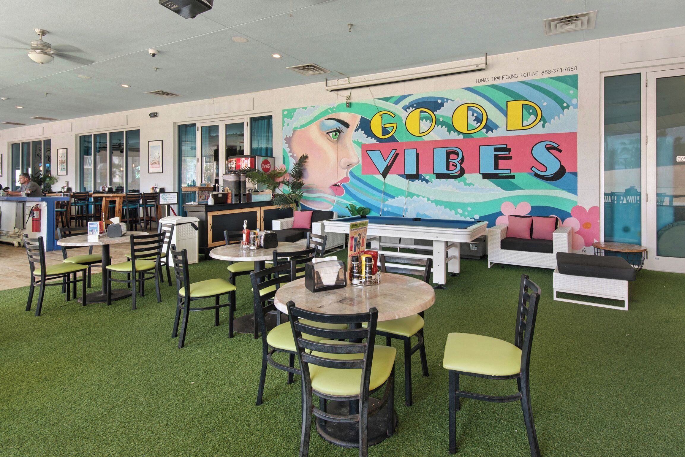 Een restaurantinterieur met kunstgras, ronde tafels en stoelen.