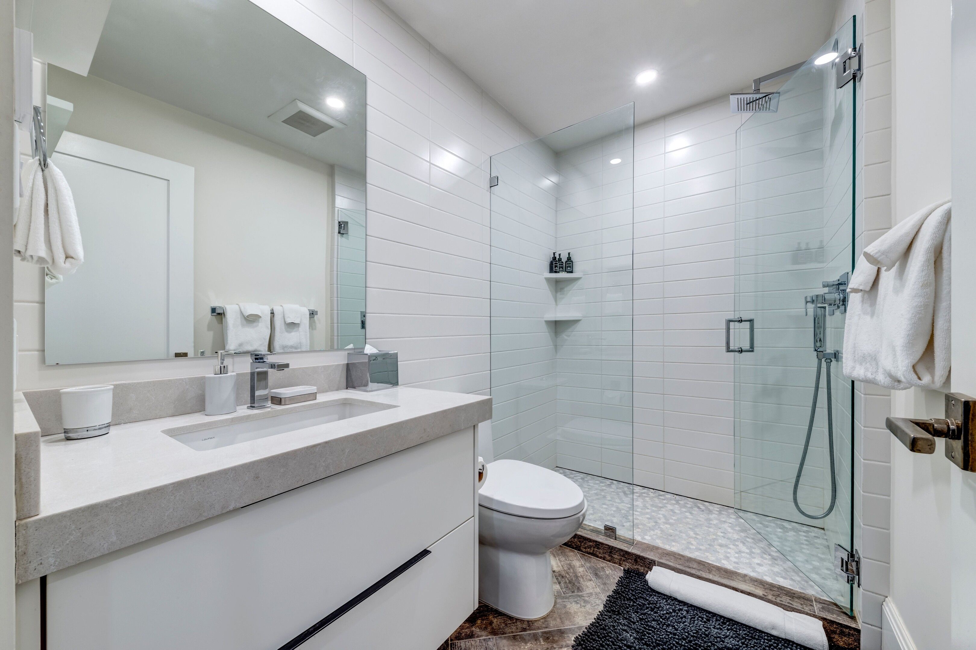 A modern bathroom with a glass shower enclosure, a white sink, and a toilet.