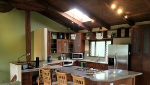 A spacious kitchen with wooden cabinets, a central island with bar stools, a microwave, and a refrigerator. - Magical 4 Bedroom 3 Bath Home with Awesome Mountain View's. New Full house AC (Princeville)