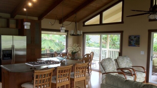 A spacious kitchen with a central island, wooden chairs, and a dining area with a view of greenery. - Magical 4 Bedroom 3 Bath Home with Awesome Mountain View's. New Full house AC (Princeville)