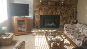 A living room with a television, a fireplace, a sofa, and a guitar. - Cute and cozy. Located in a very quiet street.   (Camdenton)