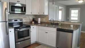 A kitchen with white cabinets, stainless steel appliances, a granite countertop, and a built-in dishwasher. - Cute and cozy. Located in a very quiet street.   (Camdenton)