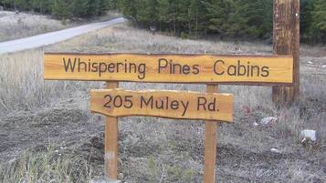 Ein Holzschild mit der Aufschrift 'Whispering Pines Cabins' und '205 Muley Rd.'