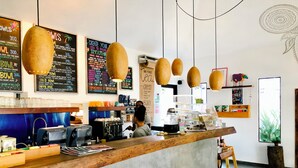 L’intérieur d’un café, avec un comptoir en bois, des panneaux affichant le menu et des lampes suspendues.