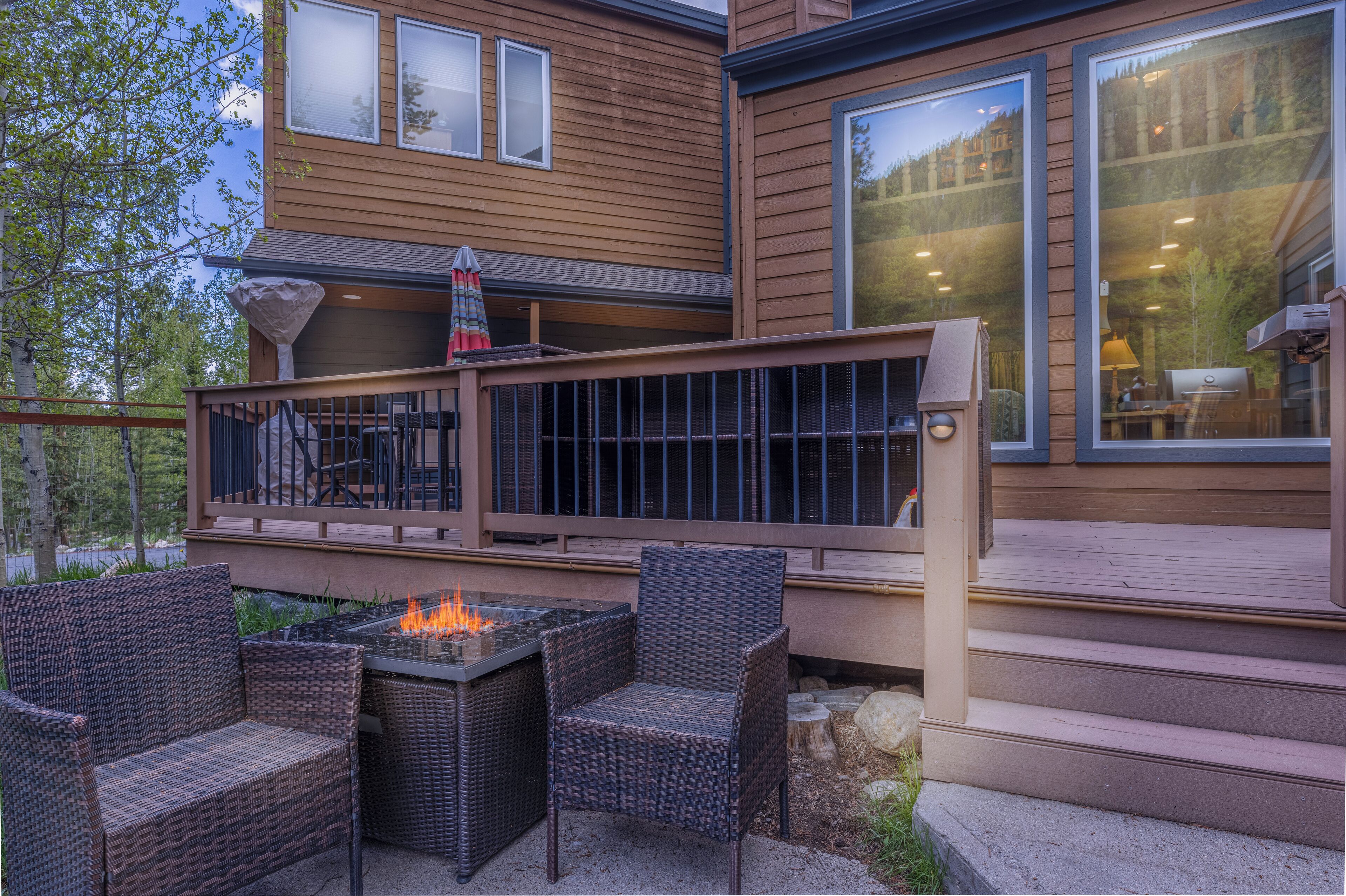 A wooden deck with wicker furniture and a fire feature.