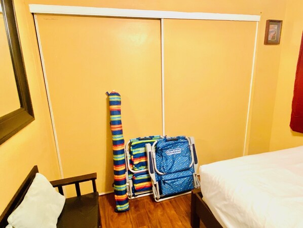 A compact hotel room with a bed, a small table, a chair, and a luggage trolley. - 2 bedroom fully furnished and all included in downtown Kona with swimming pool (Kailua kona)
