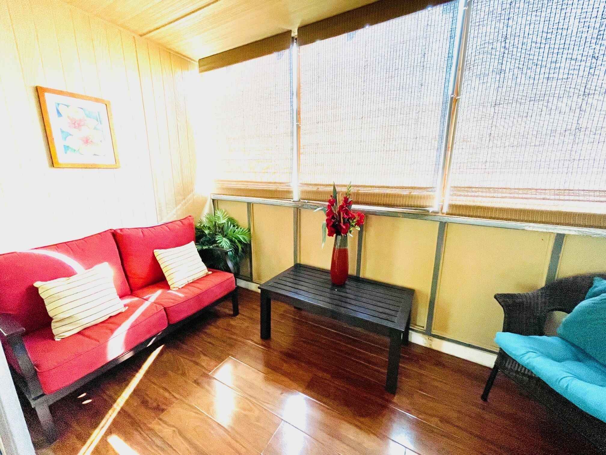 A room with a red sofa, a blue chair, a wooden coffee table, and a window with blinds.