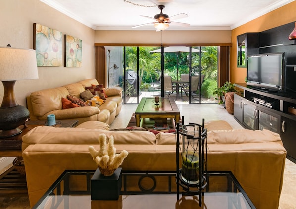 A living room with a sofa, coffee table, TV, and a view of the outdoors.