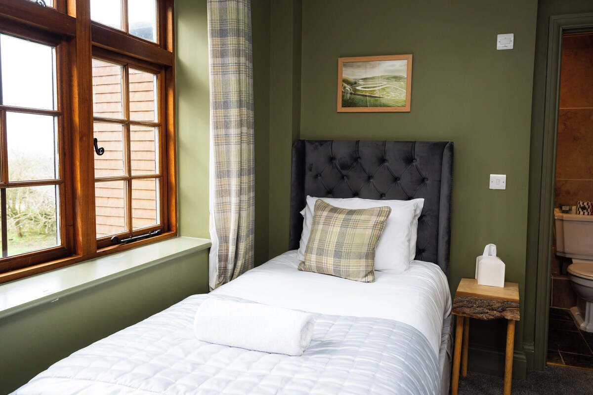 A neatly made bed with a white duvet, a headboard, and a bedside table with a tissue box.