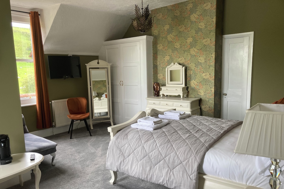 A bedroom with a bed, a dresser, a chair, a desk, and a mirror.
