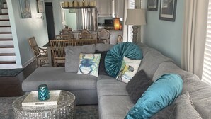 Een moderne woonkamer met een grijze modulaire bank, een ronde salontafel en een blauwe plaid.