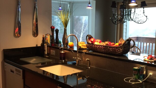 A modern kitchen with a large island, stainless steel appliances, and a large window providing natural light. - Snowcreek Condo at Sugarbush Resort-2 beds/2 baths, slopeside (Warren)