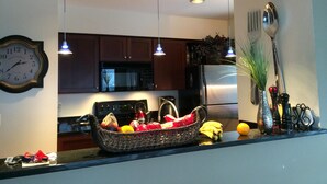 A kitchen with wooden cabinets, a microwave, a refrigerator, and a fruit basket on the counter. - Snowcreek Condo at Sugarbush Resort-2 beds/2 baths, slopeside (Warren)