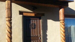 A wooden door with a metal latch, a metal roof overhang, and a concrete base. - New adobe guest house - mountain views - great location - hot tub (El Prado)