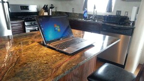 A kitchen with a laptop on a marble countertop, a sink, and a stove. - New adobe guest house - mountain views - great location - hot tub (El Prado)