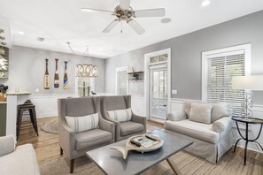 A modern living room with a grey sofa, two armchairs, a coffee table, and a ceiling fan.