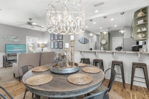 A dining area with a round table, woven placemats, and a decorative centerpiece. - Beach Chairs, Bikes & Across From Beach! ~ Seas The Day in Magnolia Cottages on 30A (Seacrest Beach)