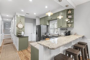 A modern kitchen with a central island, pendant lighting, and a view of the adjacent living area. - Beach Chairs, Bikes & Across From Beach! ~ Seas The Day in Magnolia Cottages on 30A (Seacrest Beach)